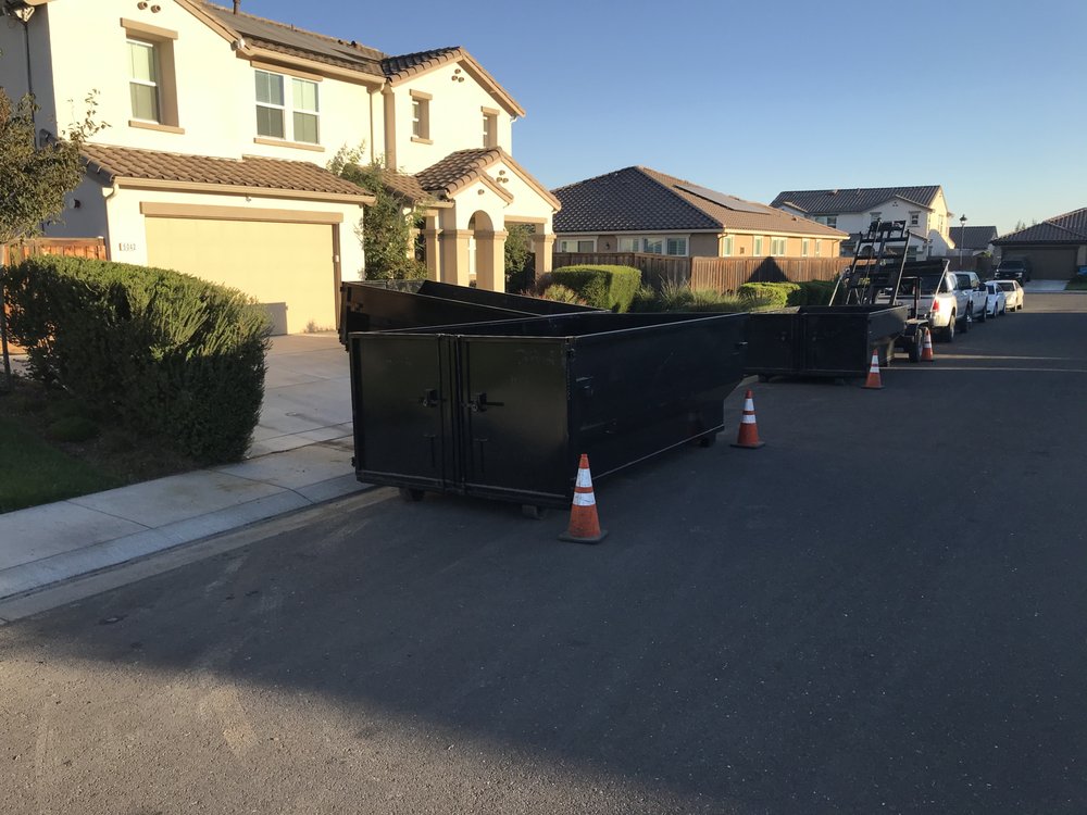 Dumpsters staged on a residential street with safety cones